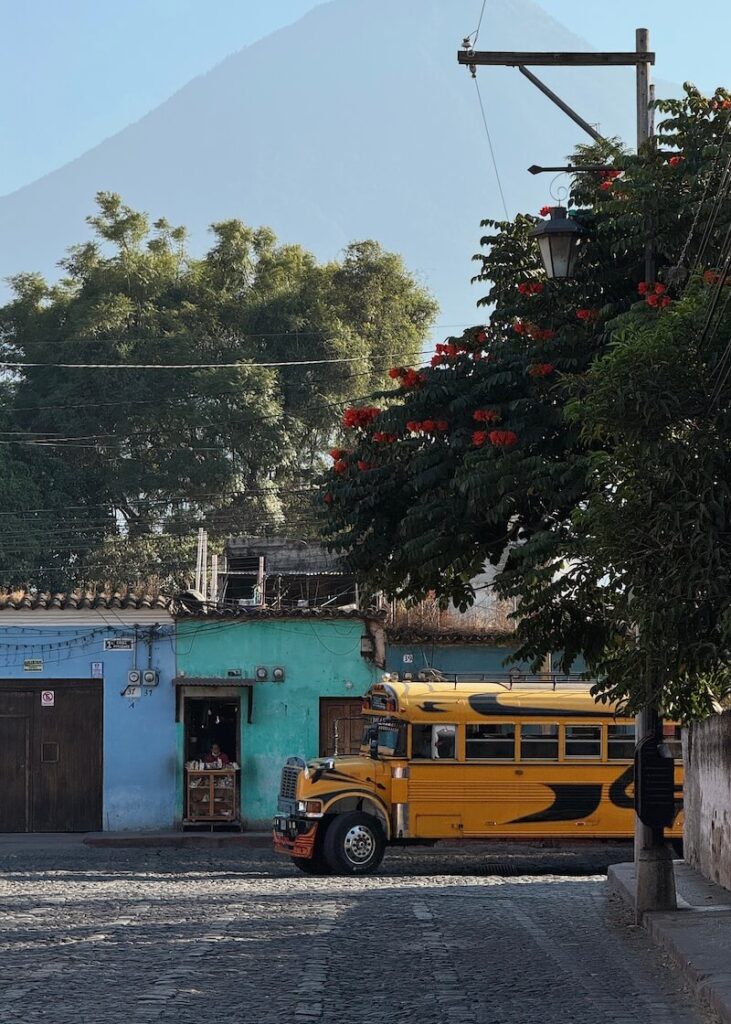 Colourful streets of Antigua Guatemala volcano background yellow chicken bus