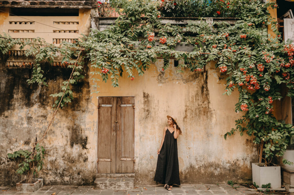 hoi an ancient town woman black dress yellow building flowers