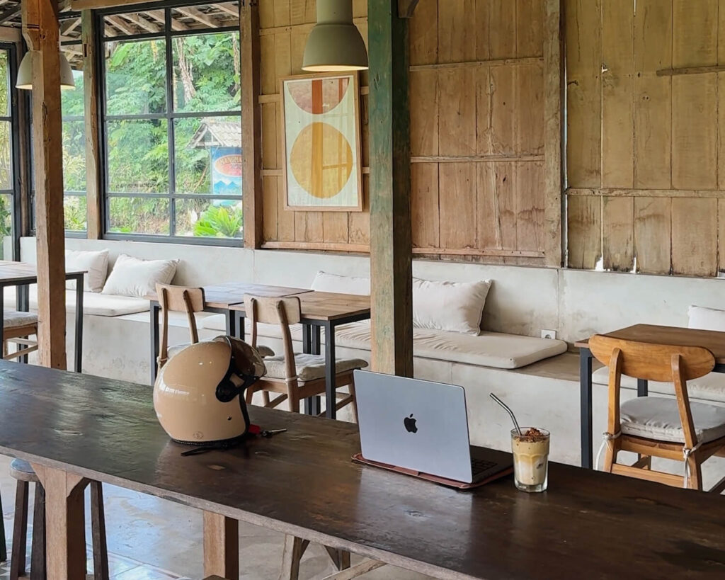 laptop next to scooter helmet in wooden cafe