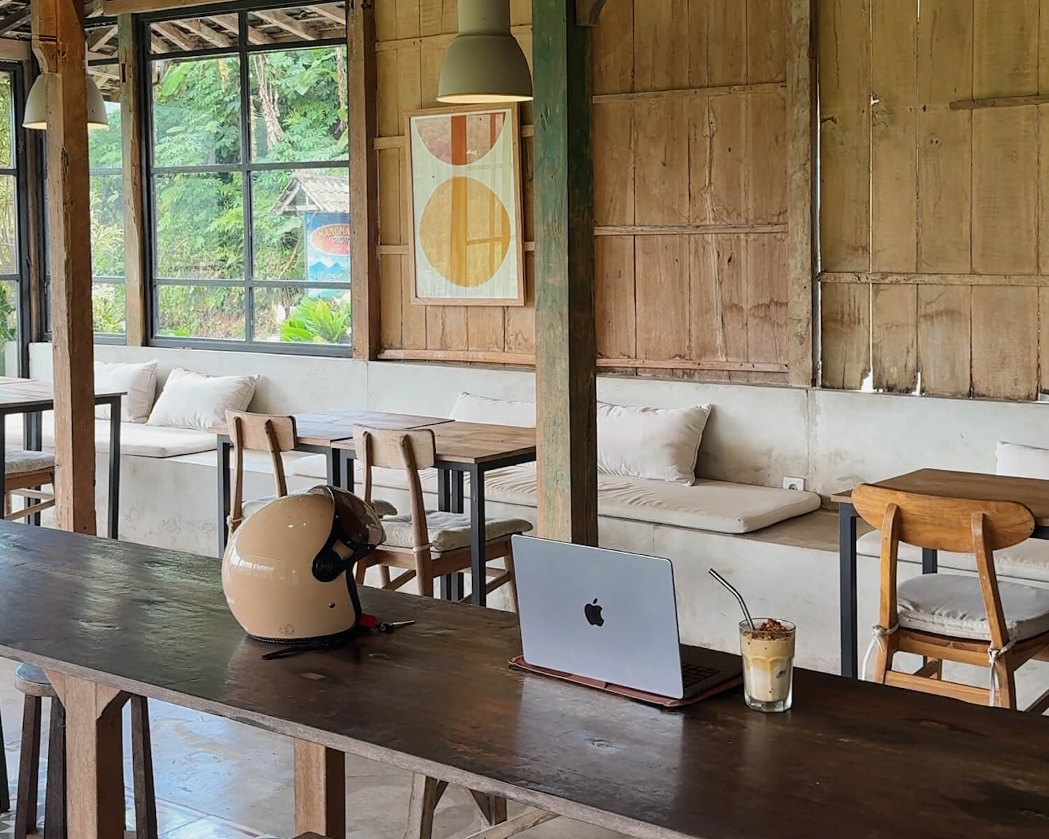 laptop next to scooter helmet in wooden cafe