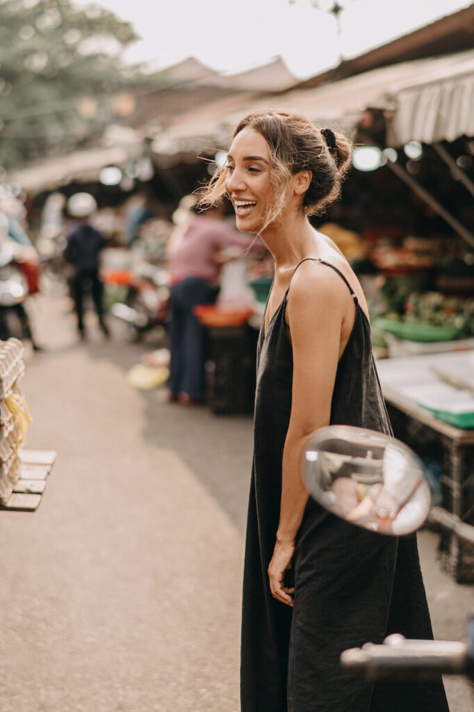 woman in black dress walking through local market hoi an vietnam