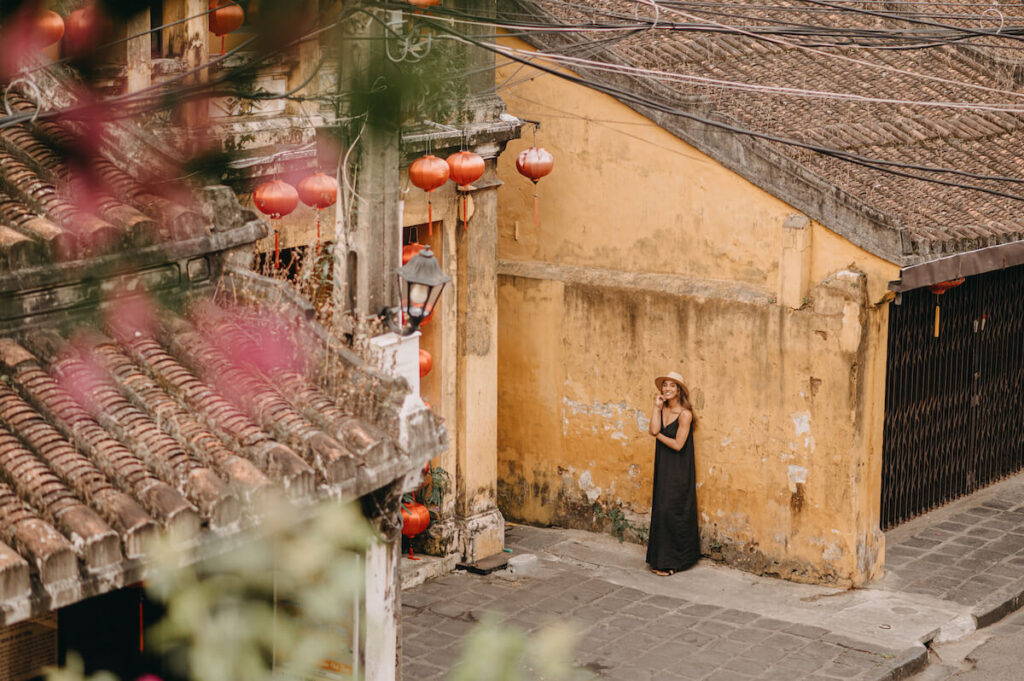 woman in black dress in ancient town hoi an yellow buildings lanterns