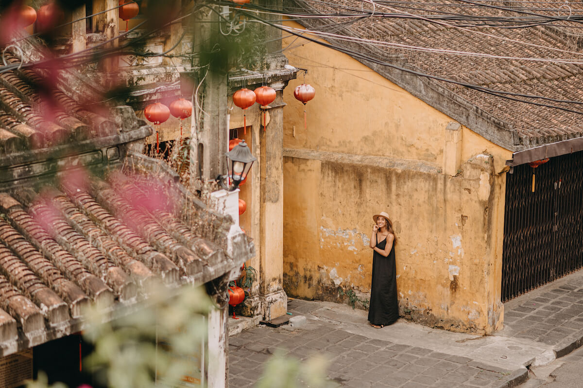 woman in black dress in ancient town hoi an yellow buildings lanterns