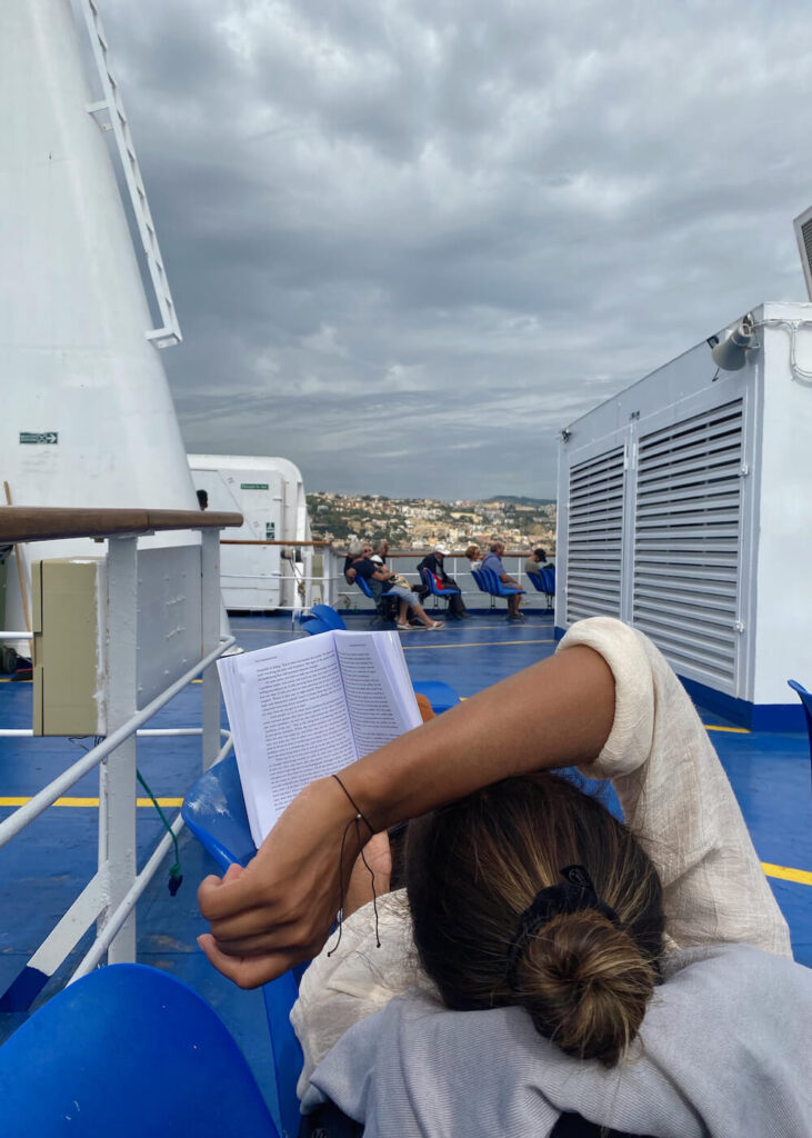 ferry ride from naples to ischia island italy reading book on deck