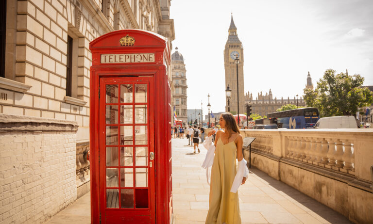 woman in london next to red phone box and big ben in the background